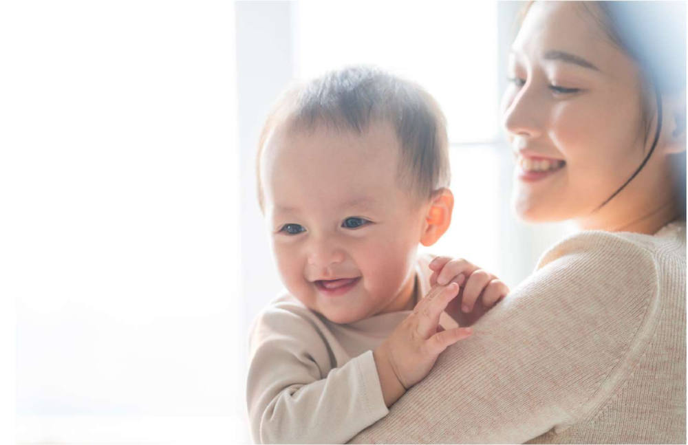 Seorang ibu muda yang sehat bermain dengan gembira dengan bayinya